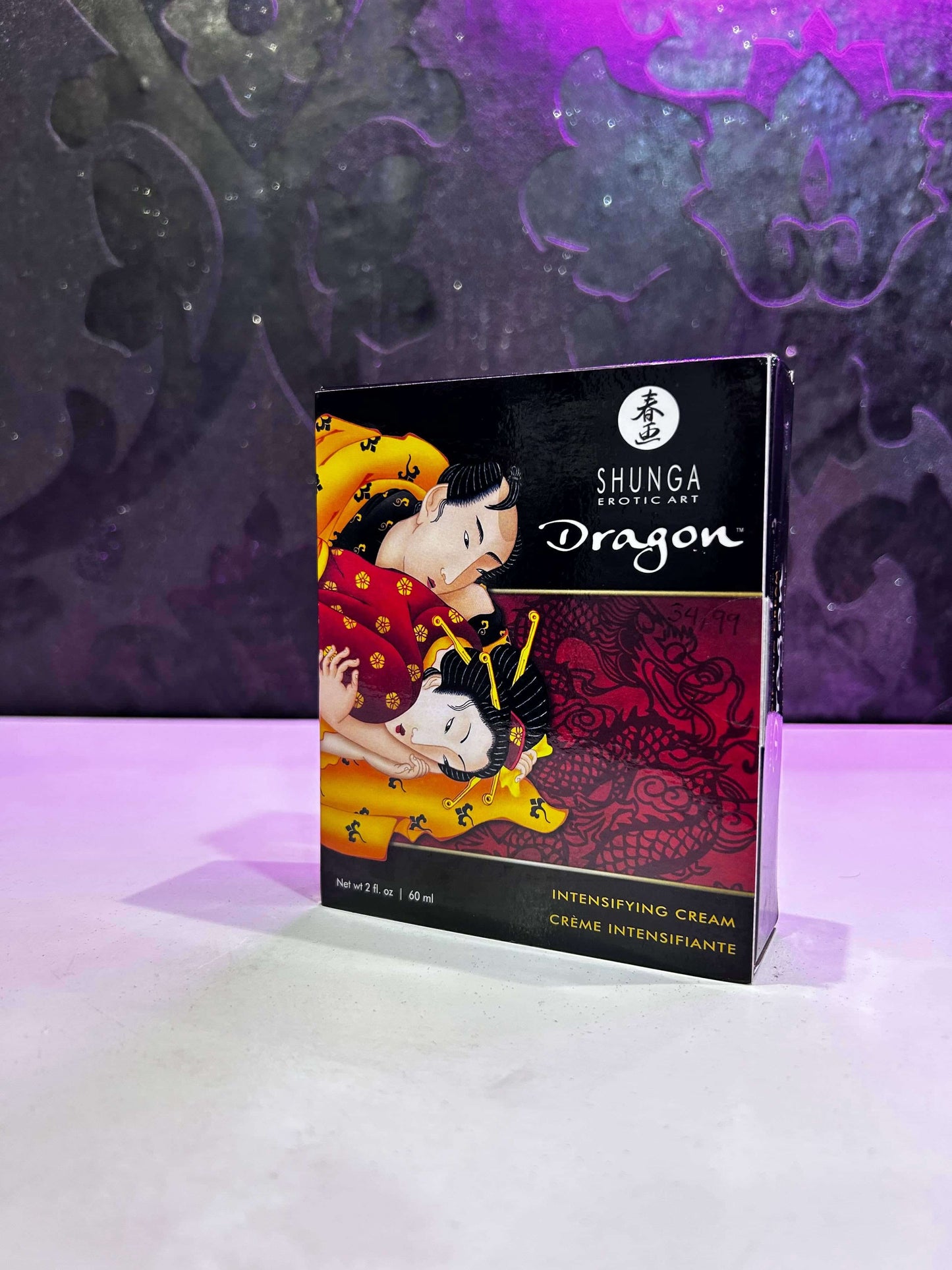 Envase de Shunga Dragon Intensifying Cream con diseño artístico sobre fondo decorativo