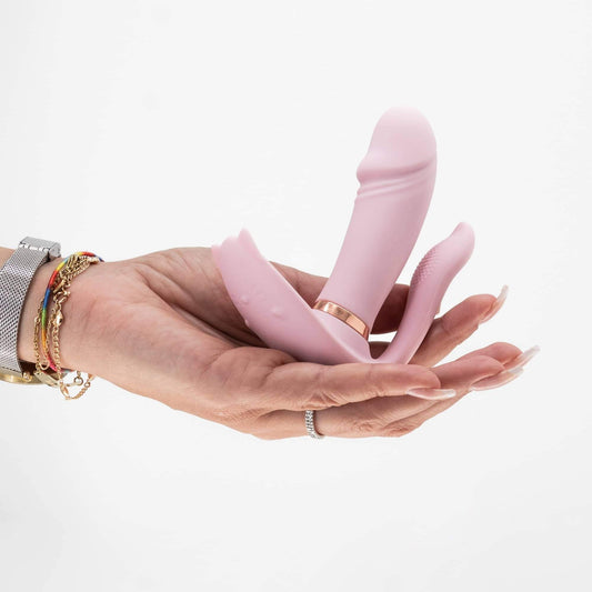 Mano sosteniendo el vibrador vaginal Fritz, de color rosa, con diseño moderno y funciones de vibración y calentamiento.