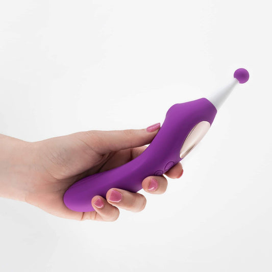 Succionador vibrador Trinity en color púrpura, sosteniendo en mano, con punta redondeada y botones de control.